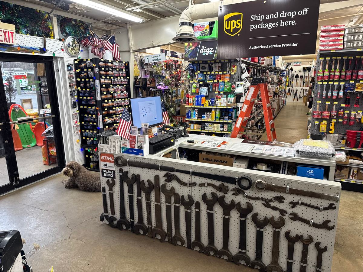 The checkout counter, its front hung with a row of very large antique wrenches, under a UPS sign; Herbert lies on the floor by the door